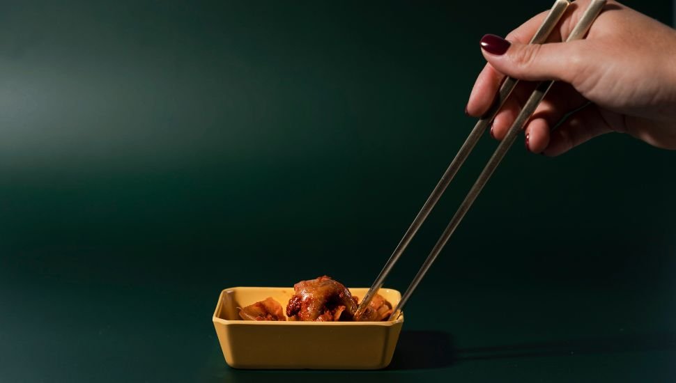 a person taking kimchi from small bowl