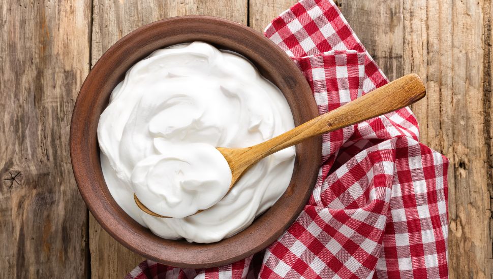 image of Yogurt in a wooden bowl and wooden spoon