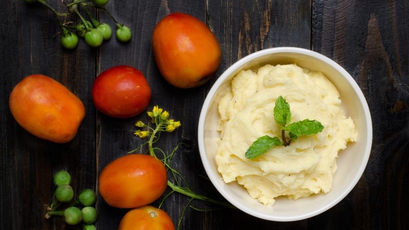 Mashed potatoes in bowl and some tomatoes