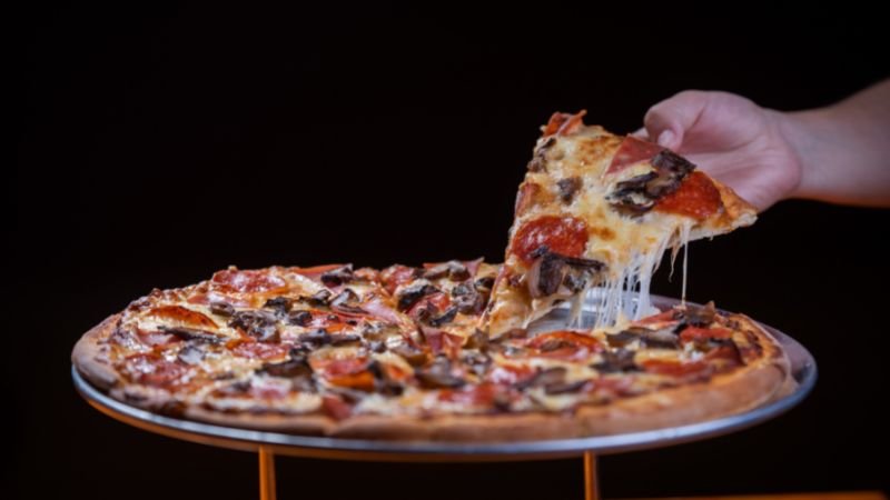 a guy taking out a slice of pizza