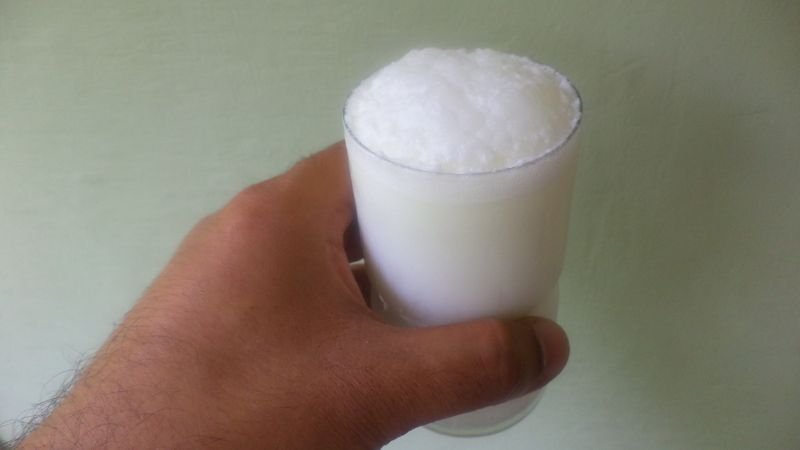 a person holding buttermilk glass