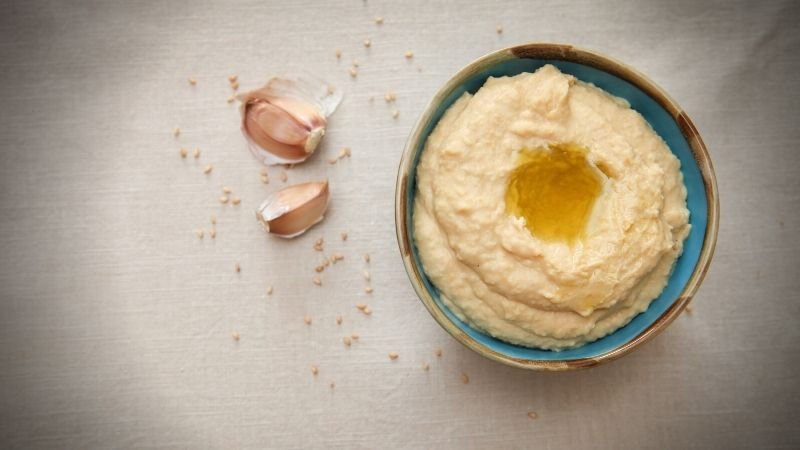 image of hummus in bowl with two garlics