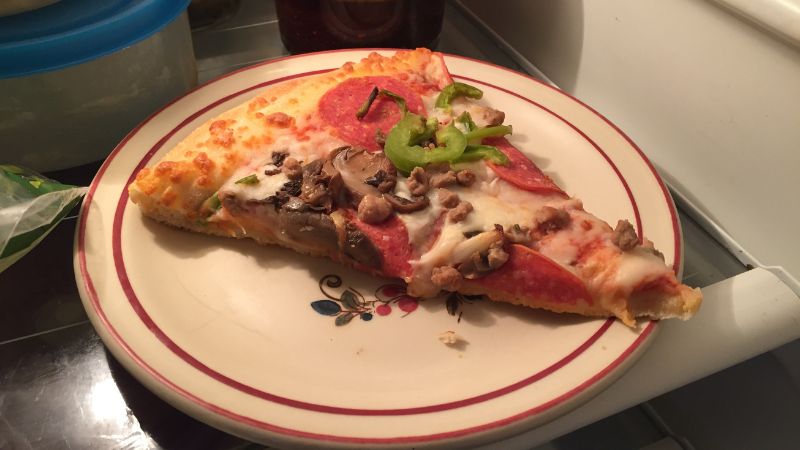 Slice of pizza on plate in fridge