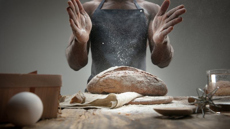 chef sprinkling flour on bread