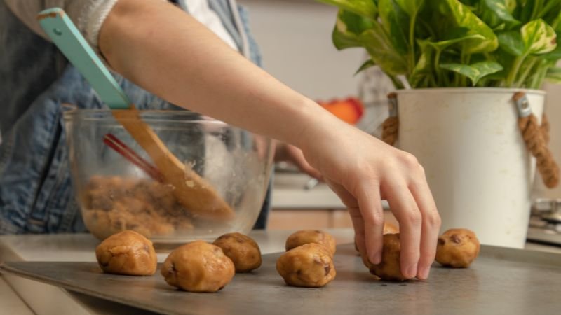 women placing cookie dough on tray