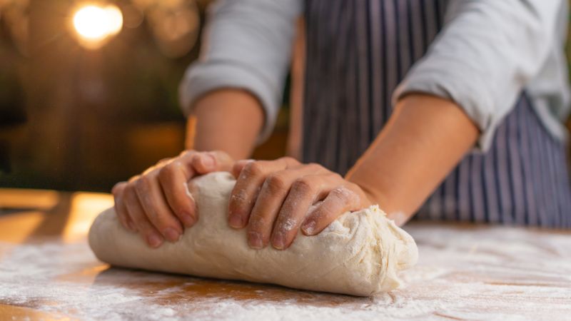 a person showing how to knead pizza dough