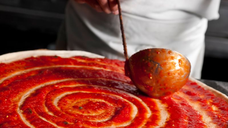close up image of pizza sauce on dough