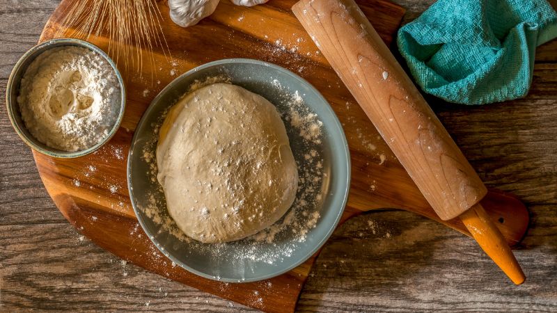 image of pizza dough in a bowl and with flour