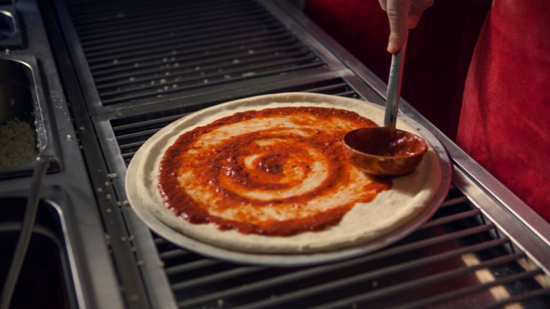 image of pouring sauce on pizza